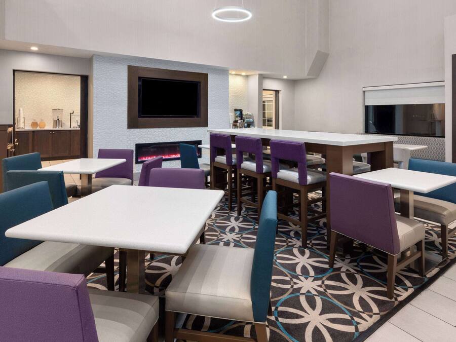 Un restaurante moderno con varias mesas y sillas, un televisor de pantalla plana en la pared y un suelo con diseño.