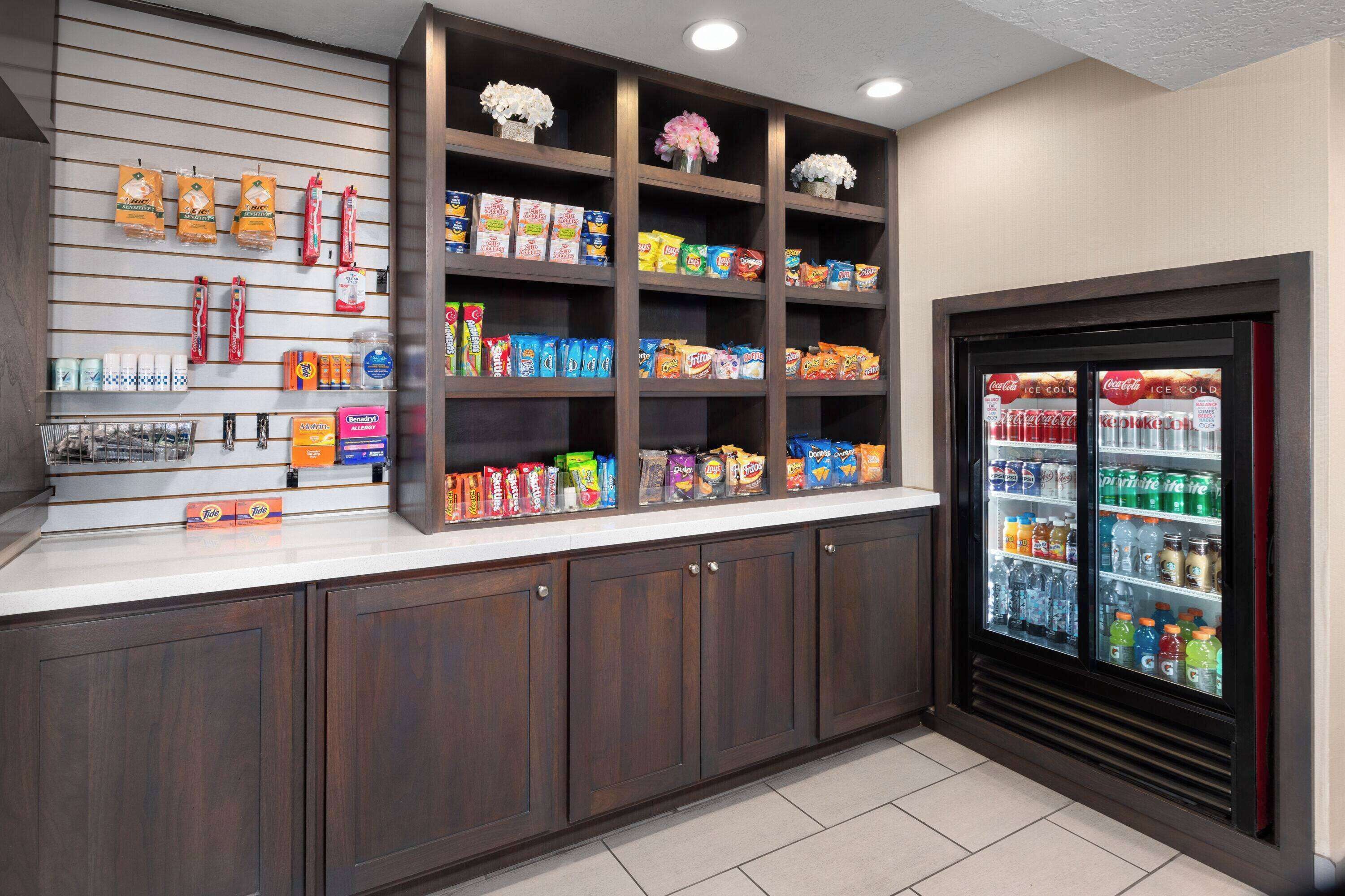 A self-service snack and beverage station with various packaged goods and a refrigerated drink dispenser.