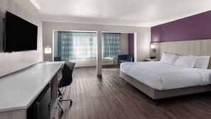 A hotel room with a bed, a desk, a chair, a TV, and a window with curtains. - La Quinta Inn & Suites by Wyndham North Orem (Orem)