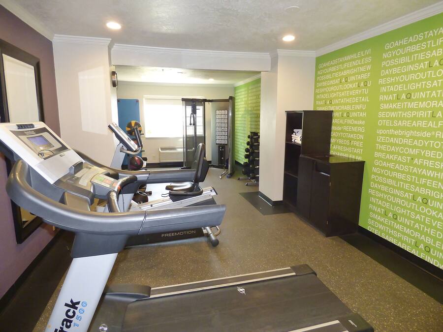 A gym with a treadmill, weights, and a wall with motivational text.
