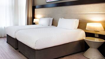 A hotel room with a large bed, two bedside tables, a lamp, and a framed picture on the wall.