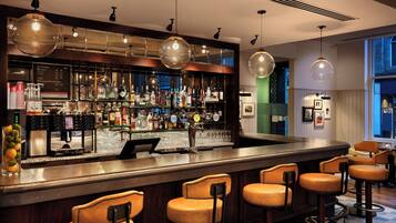 A bar area with a counter, stools, and a variety of bottles and glasses.