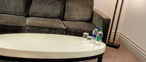 A room with a round table, a sofa, and a floor lamp.