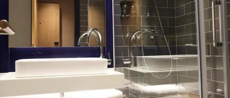A modern bathroom with a glass-enclosed shower, a white sink, and a mirror above it.