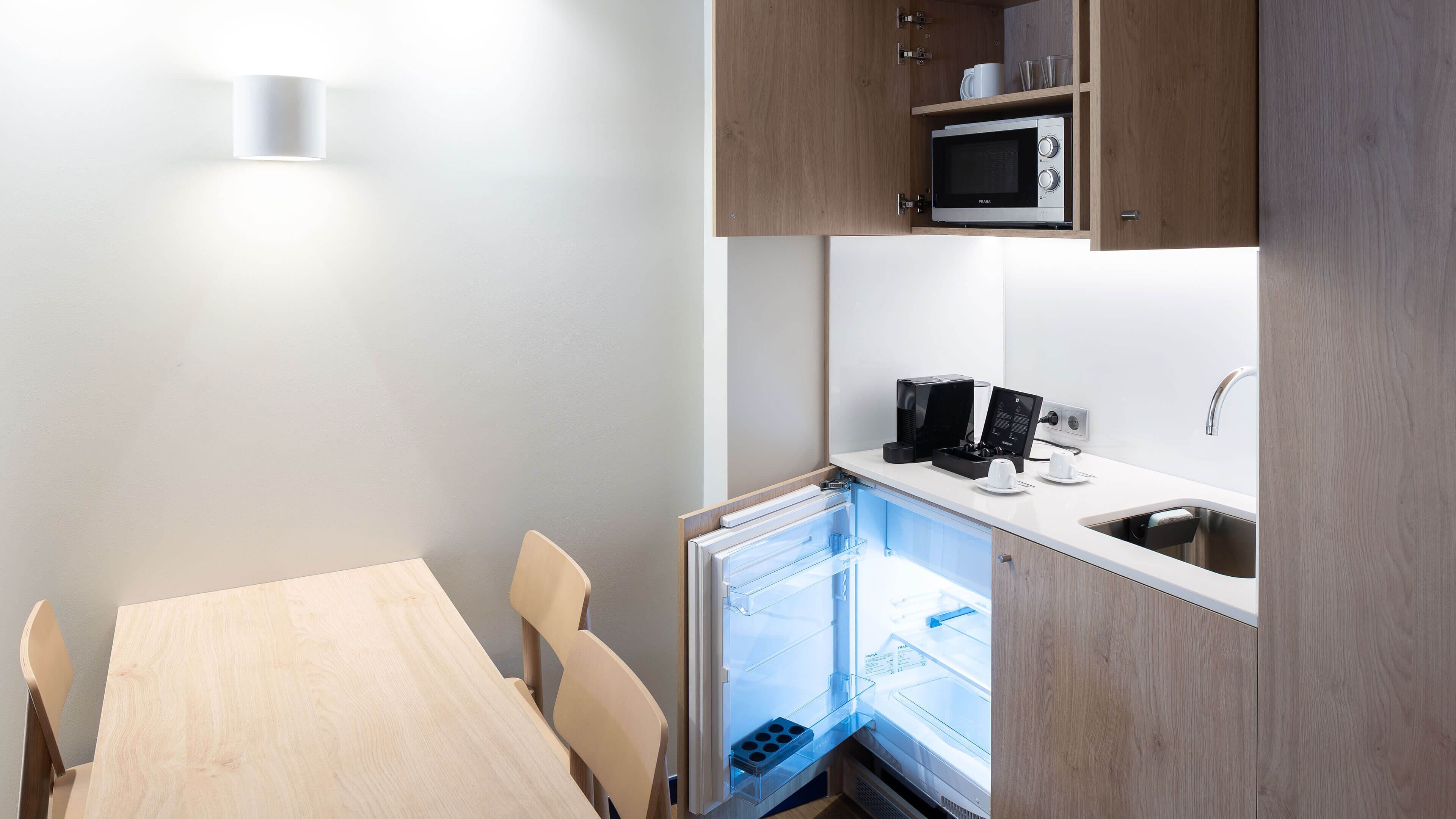 Cocina compacta con microondas, cafetera y refrigerador.