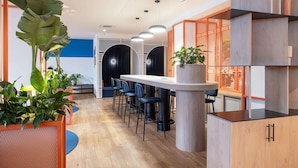 A modern interior with a long bar area, seating, and potted plants. - Holiday Inn Express and Suites Lisbon Principe Real by IHG (Lisbon)