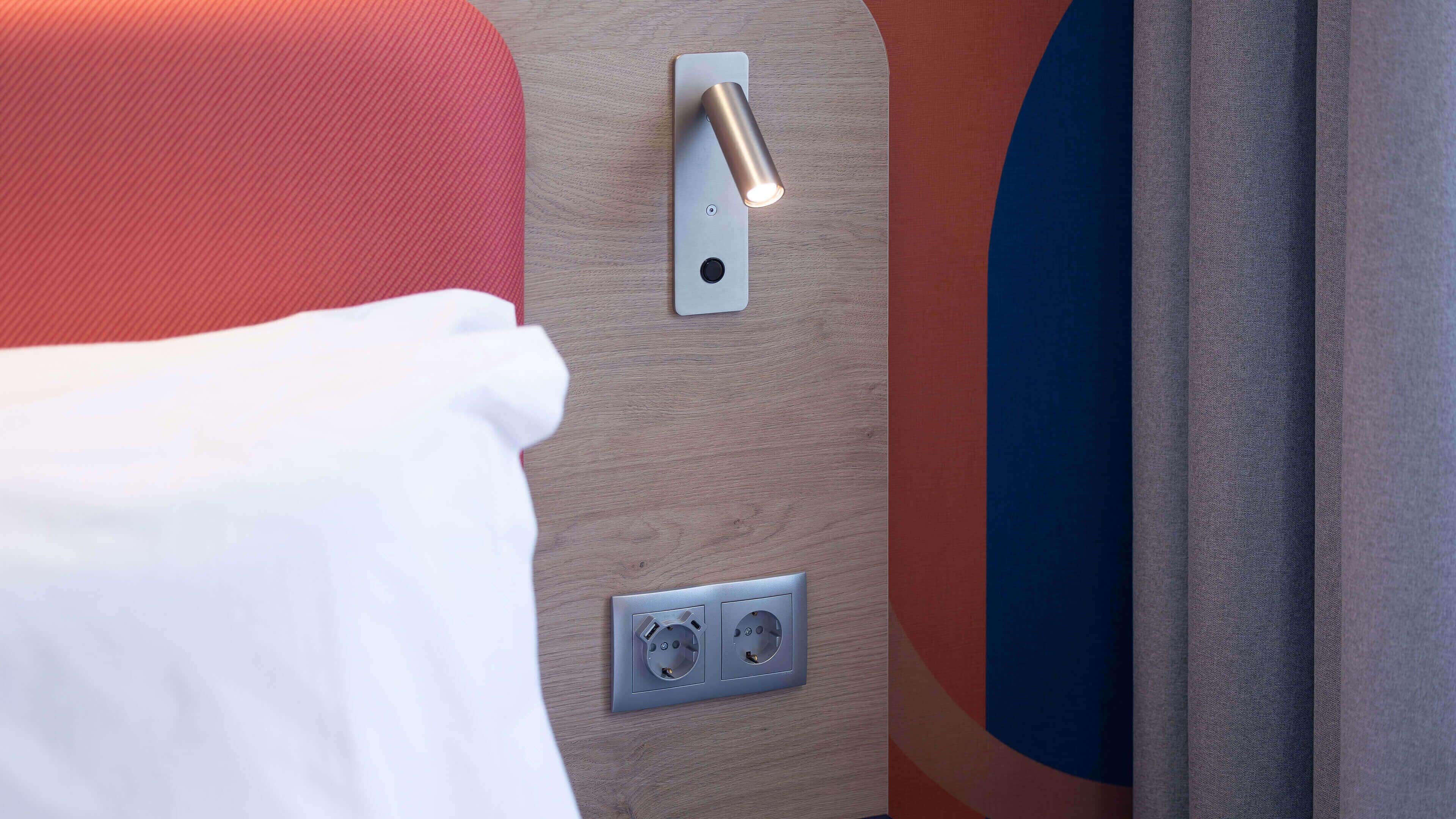 Een detail van een wandlamp, een stopcontact en een deurklink.