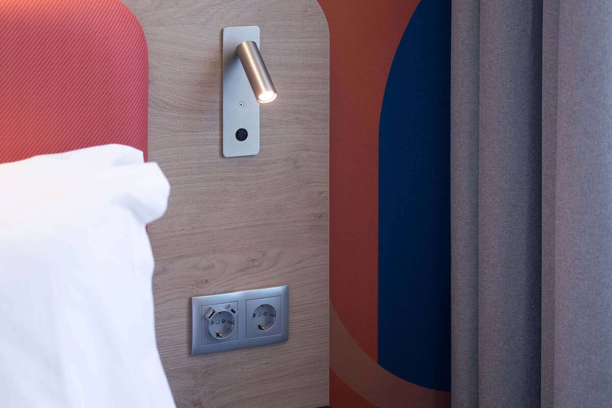 Een detail van een wandlamp, een stopcontact en een deurklink.