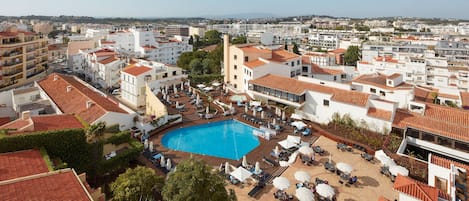 A resort with a swimming pool, outdoor seating, and a view of the city.