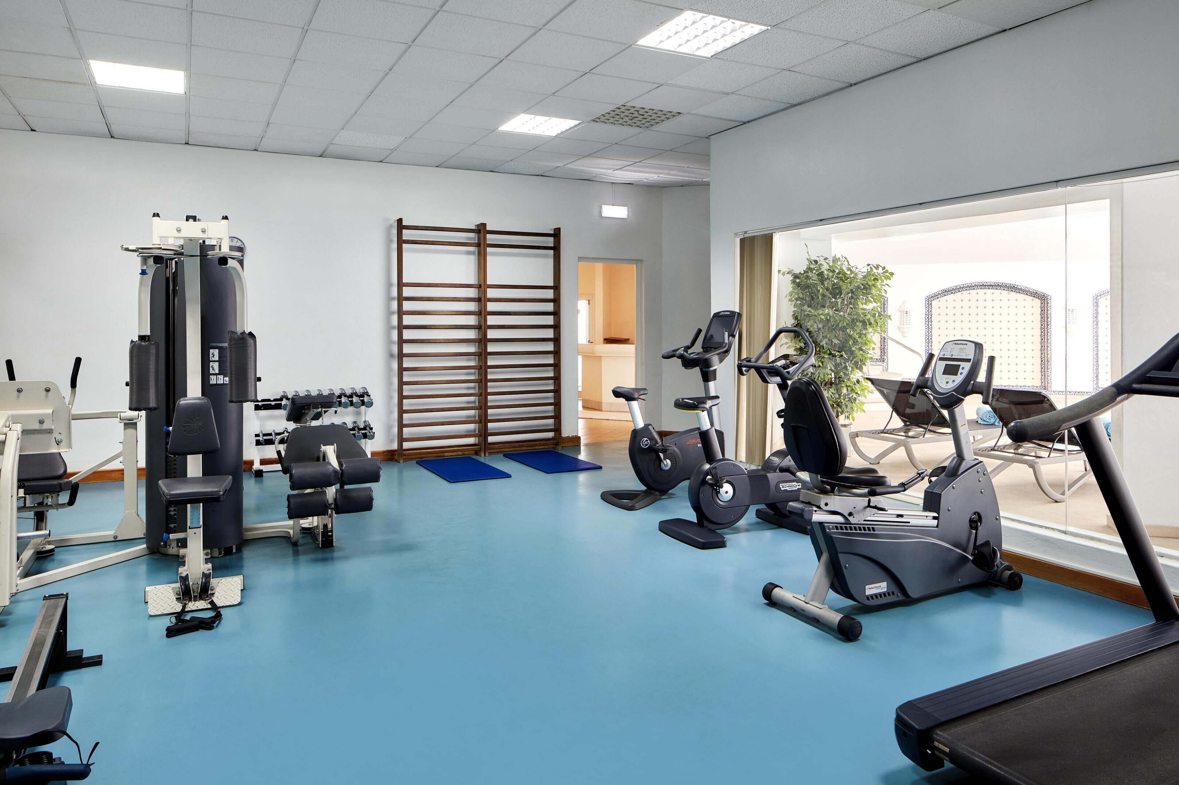 A gym with exercise equipment, a treadmill, and a large window.