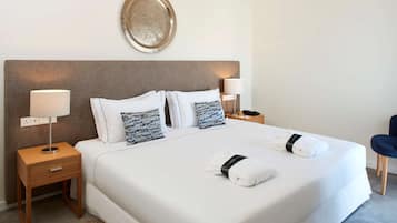 Une chambre d’hôtel avec un grand lit, deux tables de chevet, un plateau fixé au mur et une chaise.