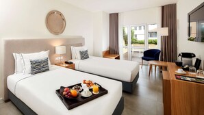 A hotel room with two beds, a desk with a coffee maker, and a breakfast tray on the beds.