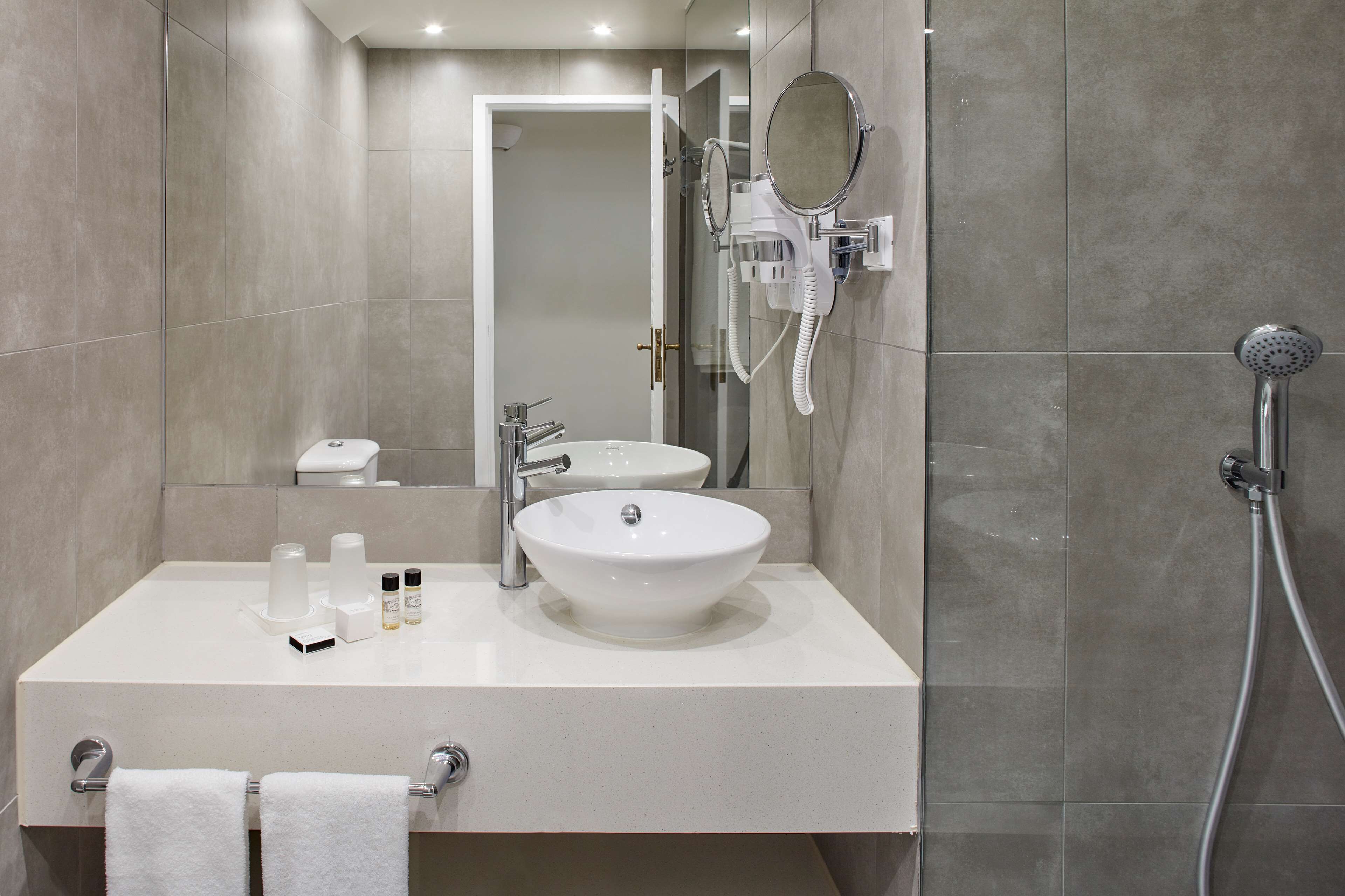 A modern bathroom with a double sink, a handheld showerhead, and a mirror.