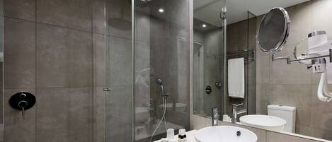 A modern bathroom with a glass-enclosed shower, a white sink, and a large mirror.