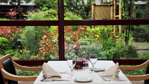 A table set for two with a view of a garden through a window. - Golden Tulip De' Medici Hotel (Bruges)