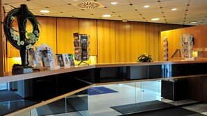A reception area with a wooden counter, glass display cases, and a decorative wreath. - Golden Tulip De' Medici Hotel (Bruges)