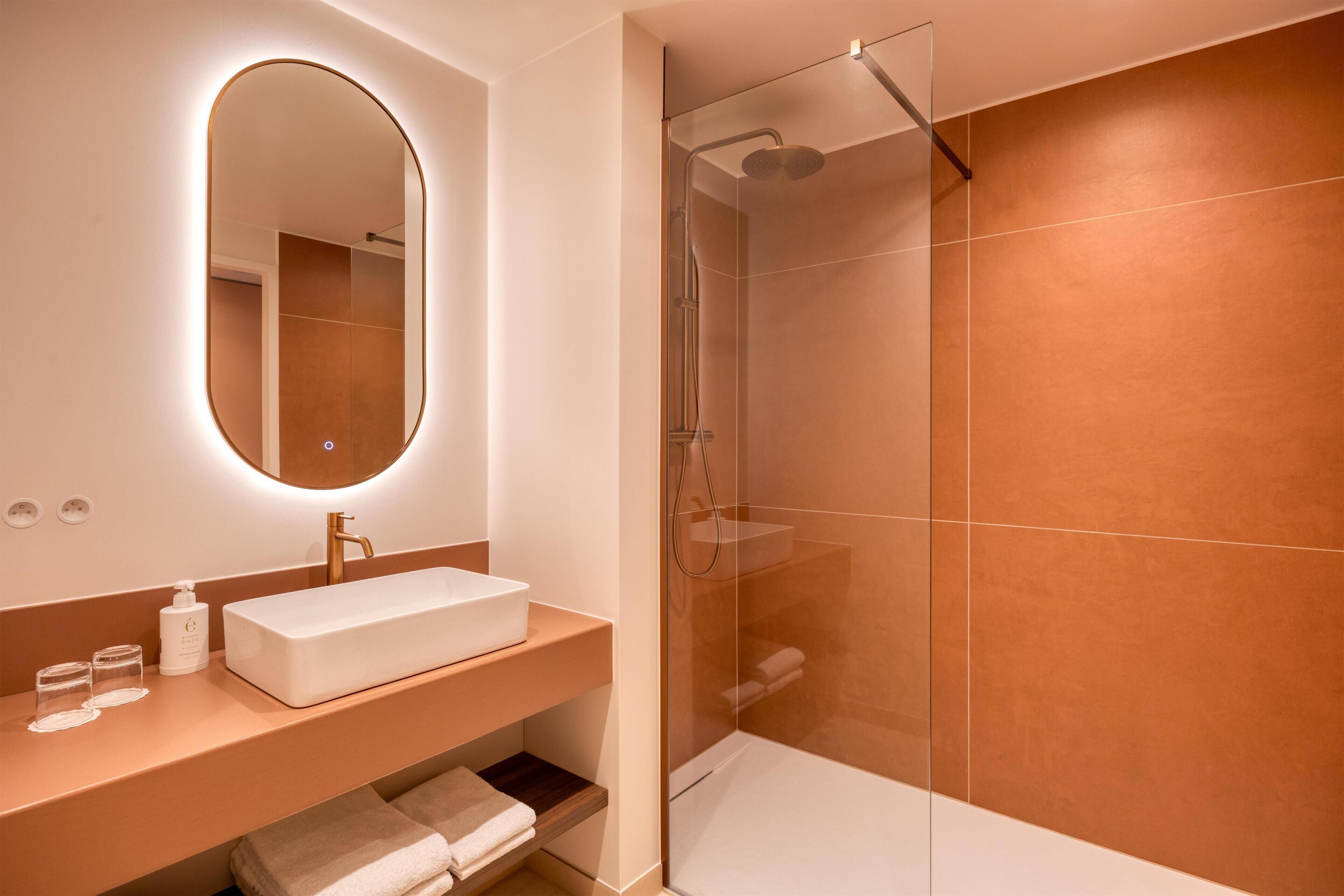 A modern bathroom with a rectangular sink, a large mirror, and a glass-enclosed shower.