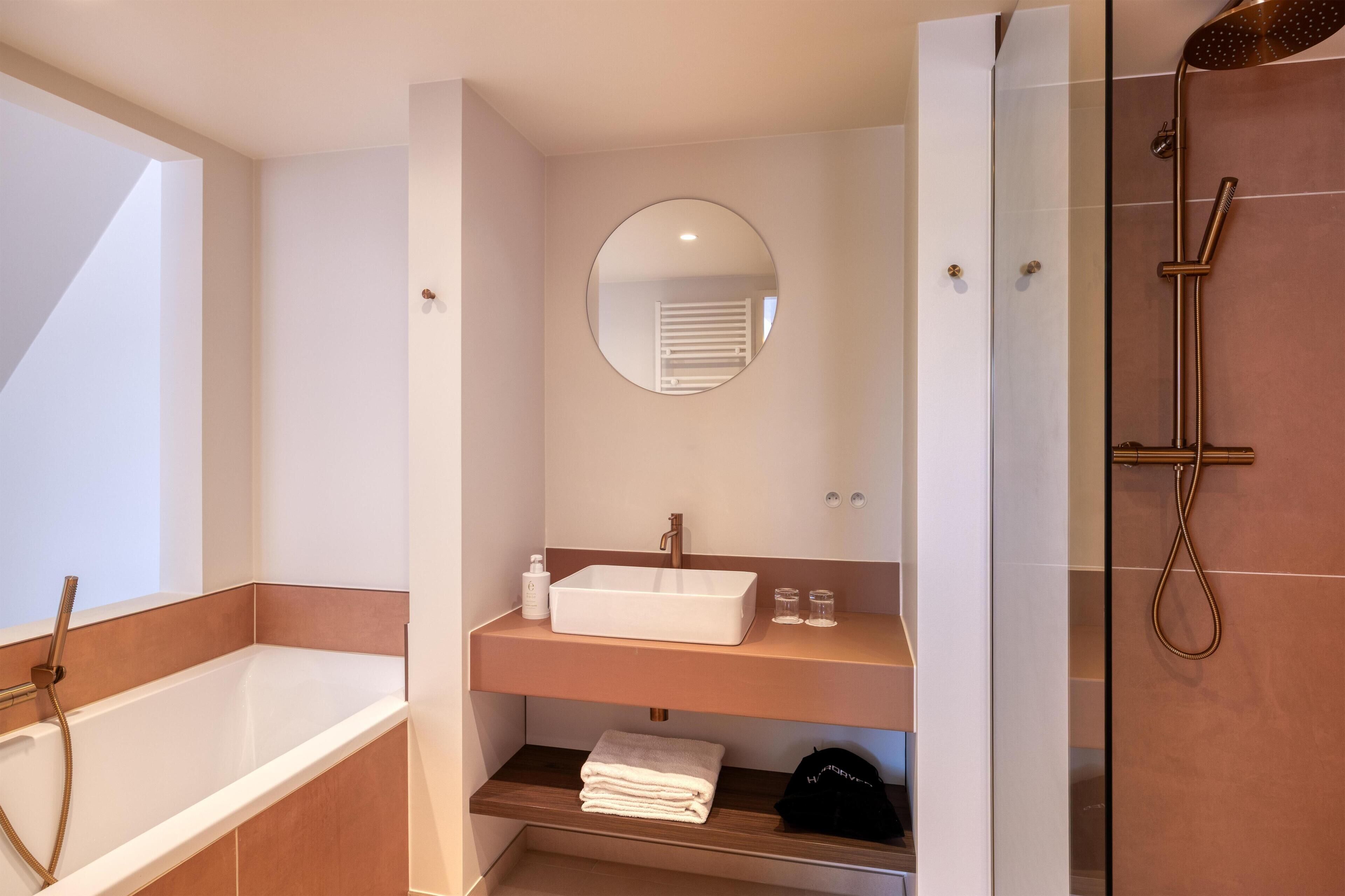 Een moderne badkamer met een badkuip, een wastafel met spiegel en een douchehoek.