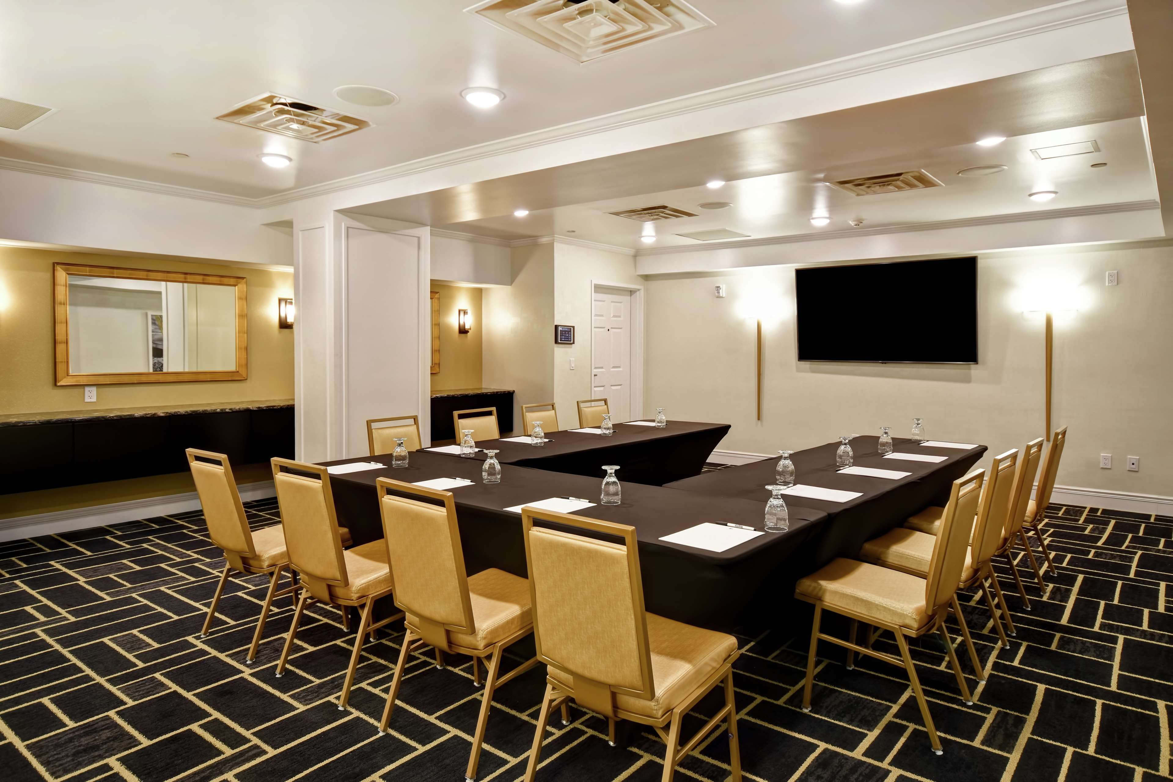 A conference room with a large table, chairs, and a flat-screen TV.