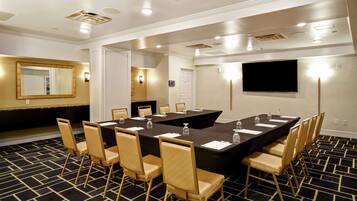 A conference room with a large table, chairs, and a flat-screen TV.