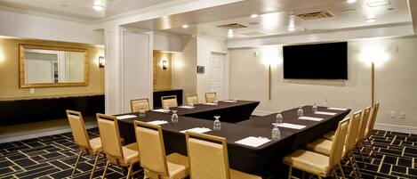 A conference room with a large table, chairs, and a flat-screen TV.