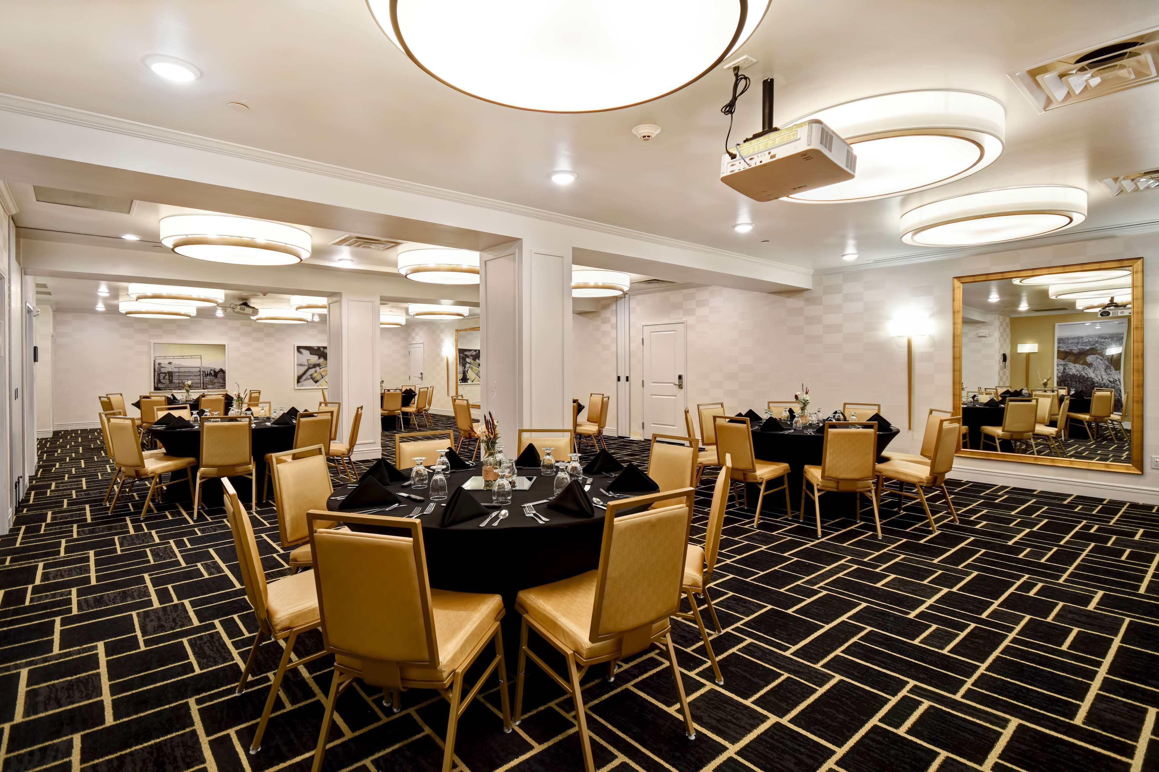 A conference room with round tables, chairs, and a large mirror.