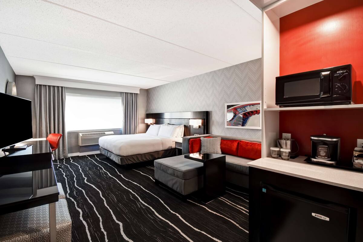 Una habitación de hotel con una cama, un escritorio, un sofá, una máquina de café y un microondas.