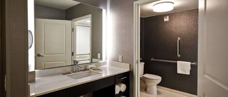 A modern bathroom with a large mirror, a sink, and a toilet.