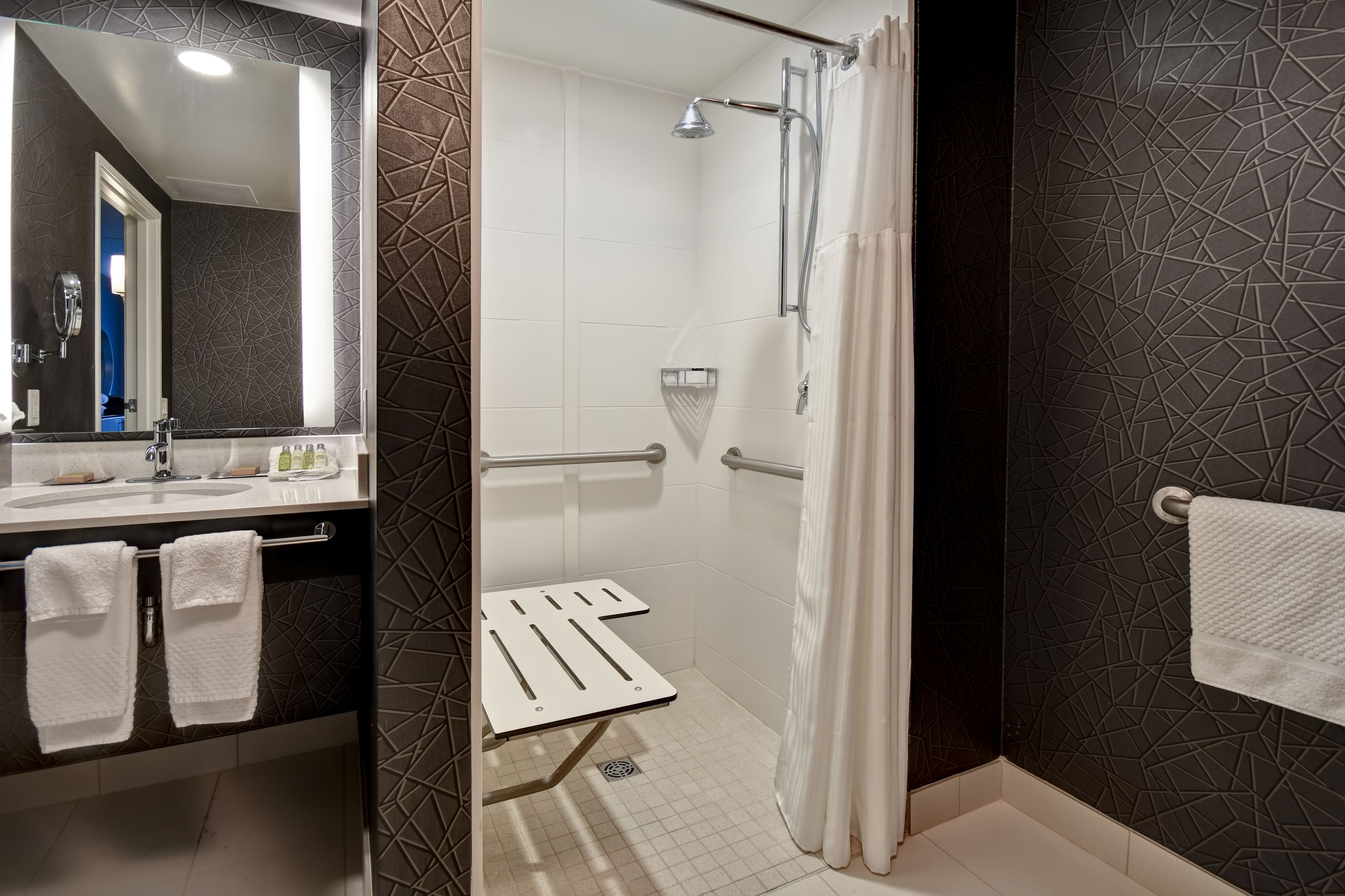 Un bagno moderno con doccia, lavandino con specchio e portasciugamani.