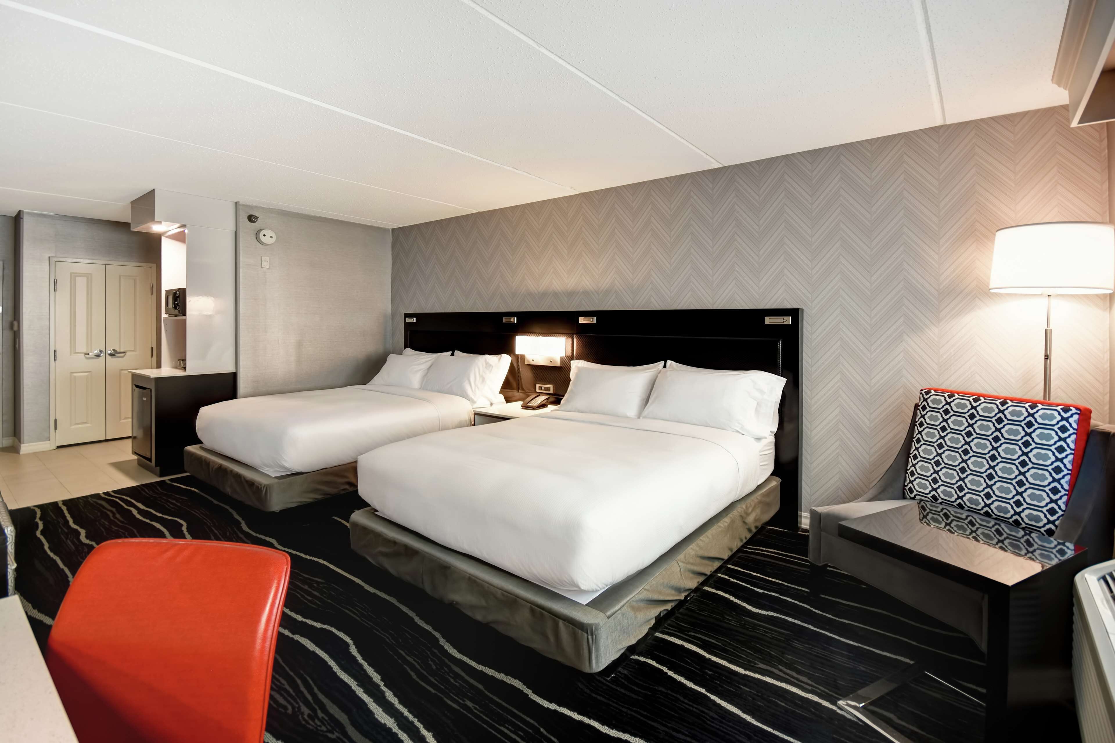 A hotel room with two beds, a desk, a chair, and a nightstand.