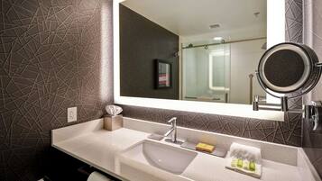 Un baño moderno con un espejo grande, un lavamanos y una cabina de ducha de vidrio.