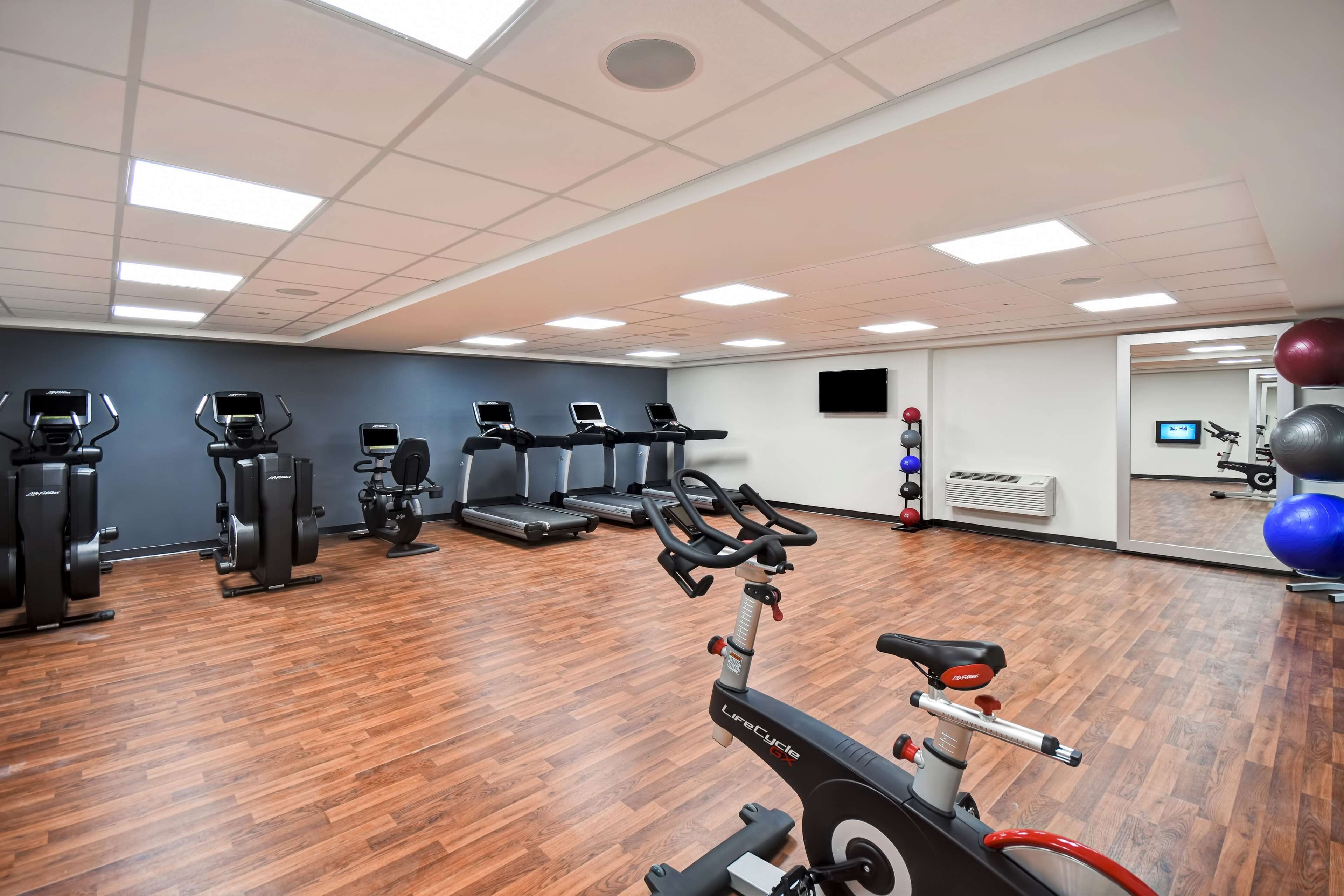 A gym with exercise equipment, treadmills, and a mirror.
