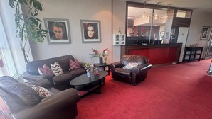Una sala de estar con alfombra roja, dos sofás de cuero, una mesita de centro y una planta.