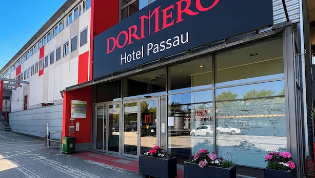 Fachada moderna de un hotel con un letrero llamativo que dice 'DORMERO Hotel Passau'.