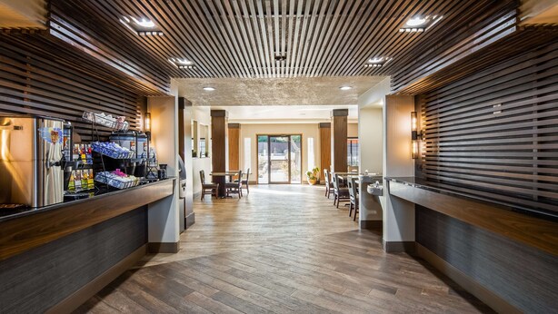 A modern hotel lobby with a central seating area, a coffee machine, and a view of the outdoor patio. - Best Western Plus Hill Country Suites (San Antonio)