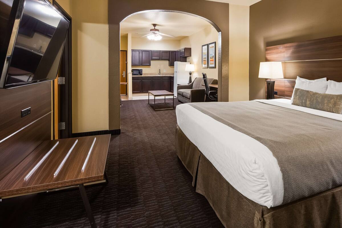 Een hotelkamer met een groot bed, een bureau, een televisie en een kitchenette.