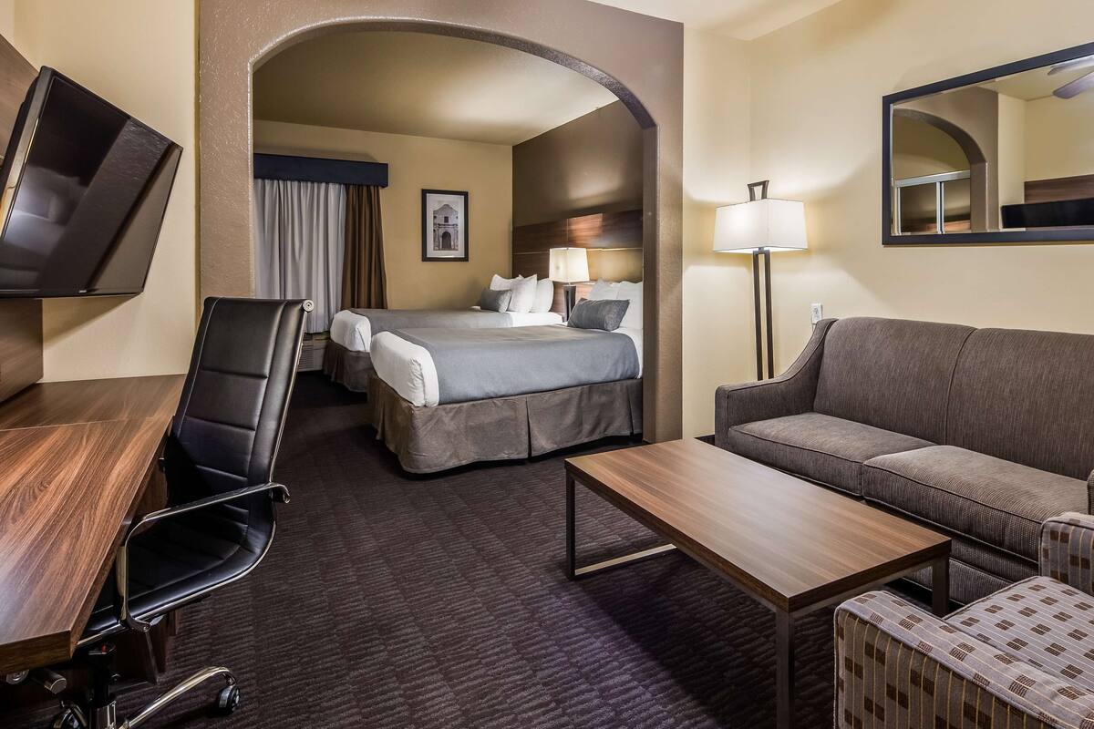 Hotelkamer met een bed, een bank, een bureau, een stoel, een televisie en een lamp.
