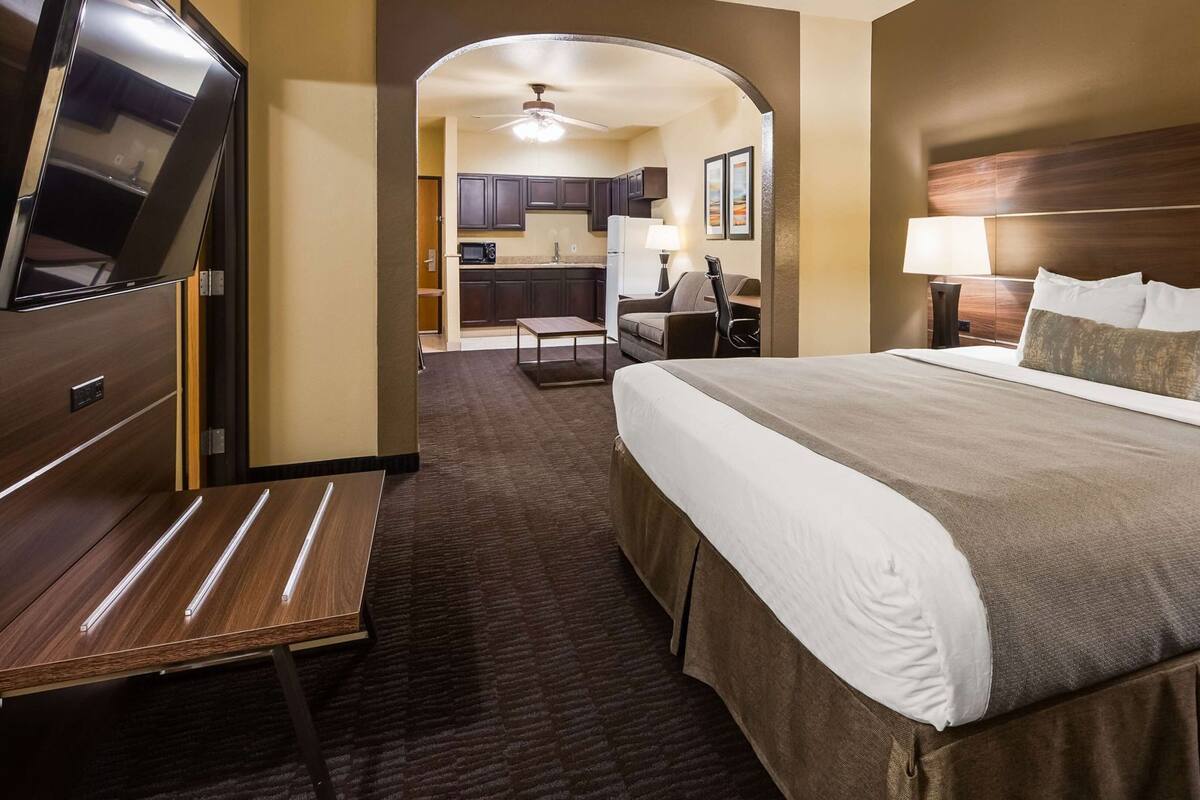 Een hotelkamer met een bed, een bureau, een televisie, een kitchenette en een badkamer.