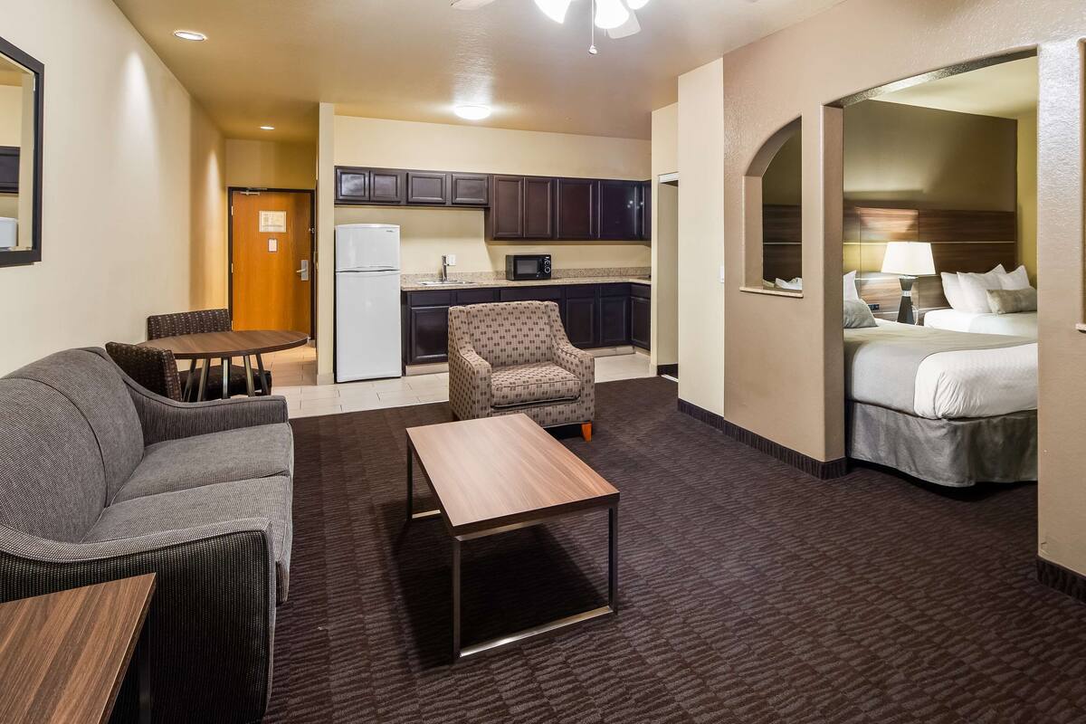 Een compacte hotelkamer met kitchenette, een bank, een klein tafeltje en een bed.