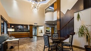 A spacious lobby with a high ceiling, a modern chandelier, a reception desk, and a staircase leading to an upper level. - Best Western Plus Hill Country Suites (San Antonio)