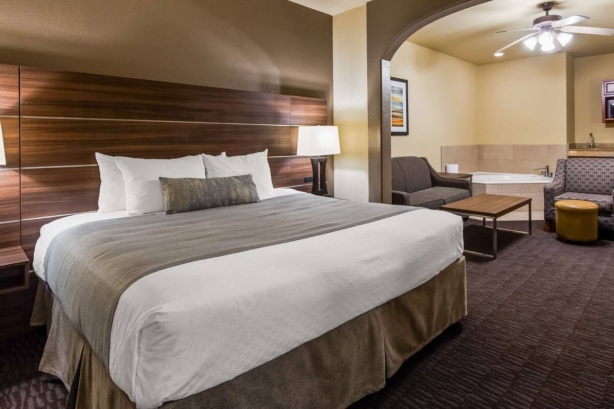 Hotelkamer met een groot bed, een bureau, een stoel, een klein tafeltje, een bank, een magnetron en een plafondventilator.