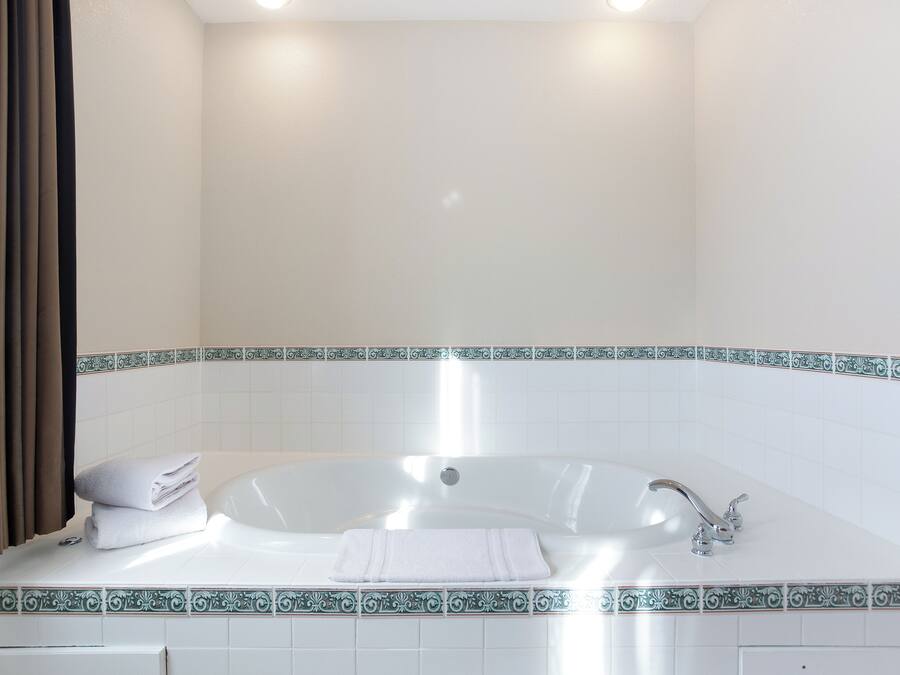 Ein Badezimmer mit einer weißen Badewanne, einem Waschbecken und einem auf dem Rand gestapelten Handtuch.