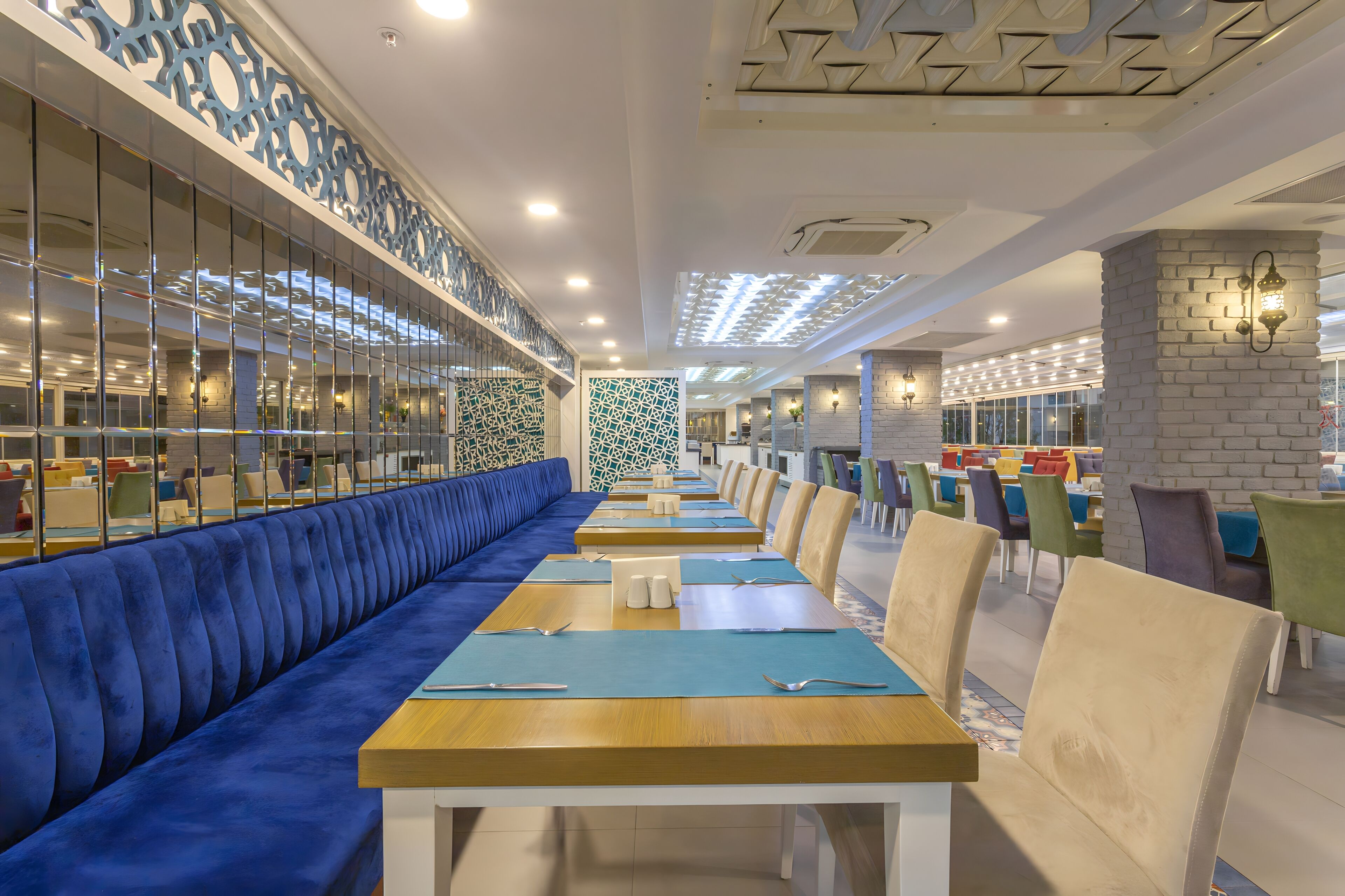 Ein modernes Restaurant mit blau gepolsterten Sitzgelegenheiten, Holztischen und Wandverzierungen mit Muster.