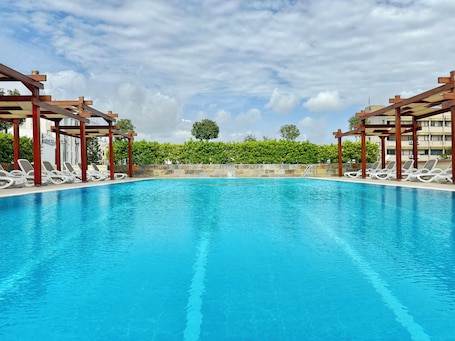 Una piscina al aire libre de temporada, sombrillas