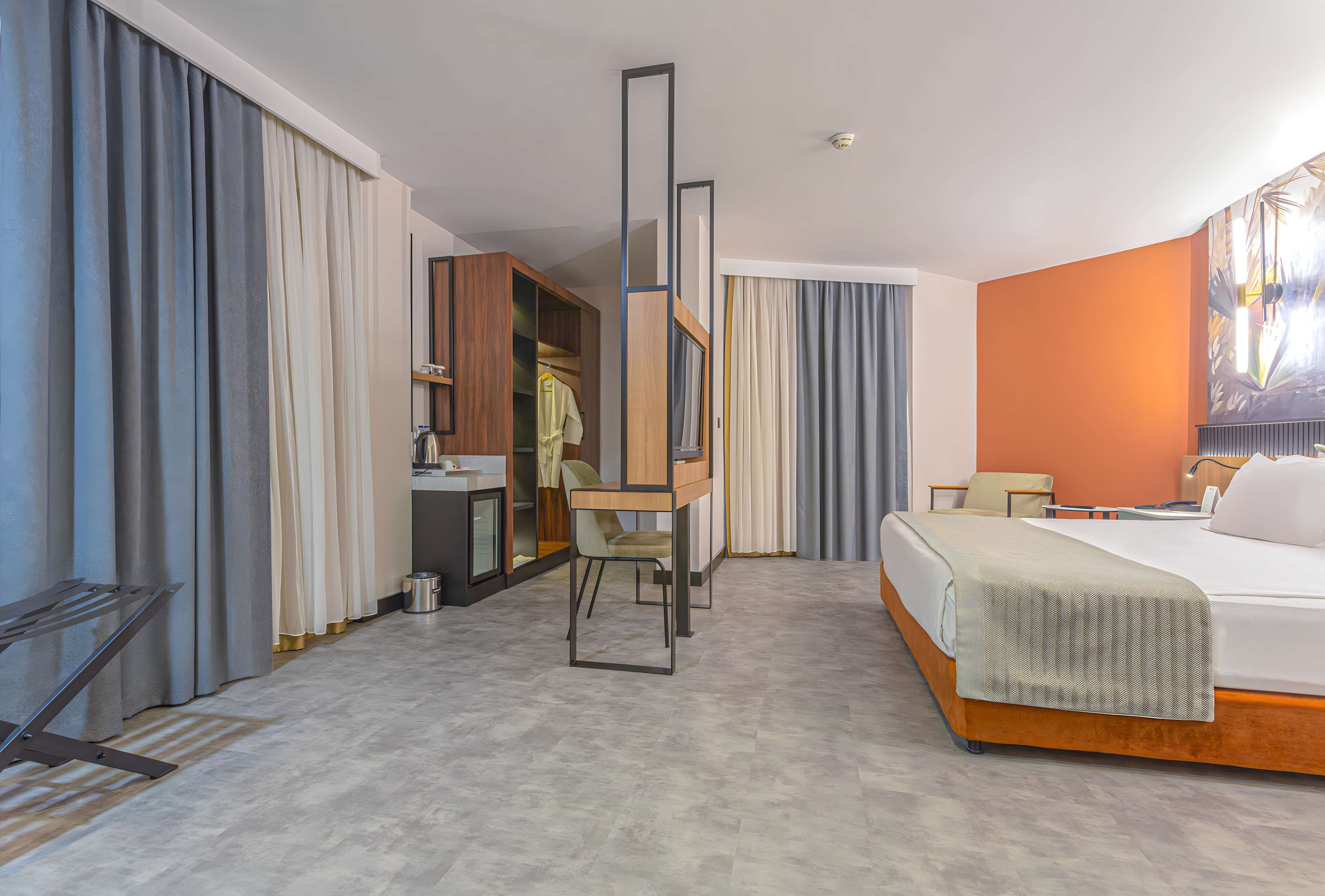 Una habitación de hotel moderna con cama, escritorio y armario.
