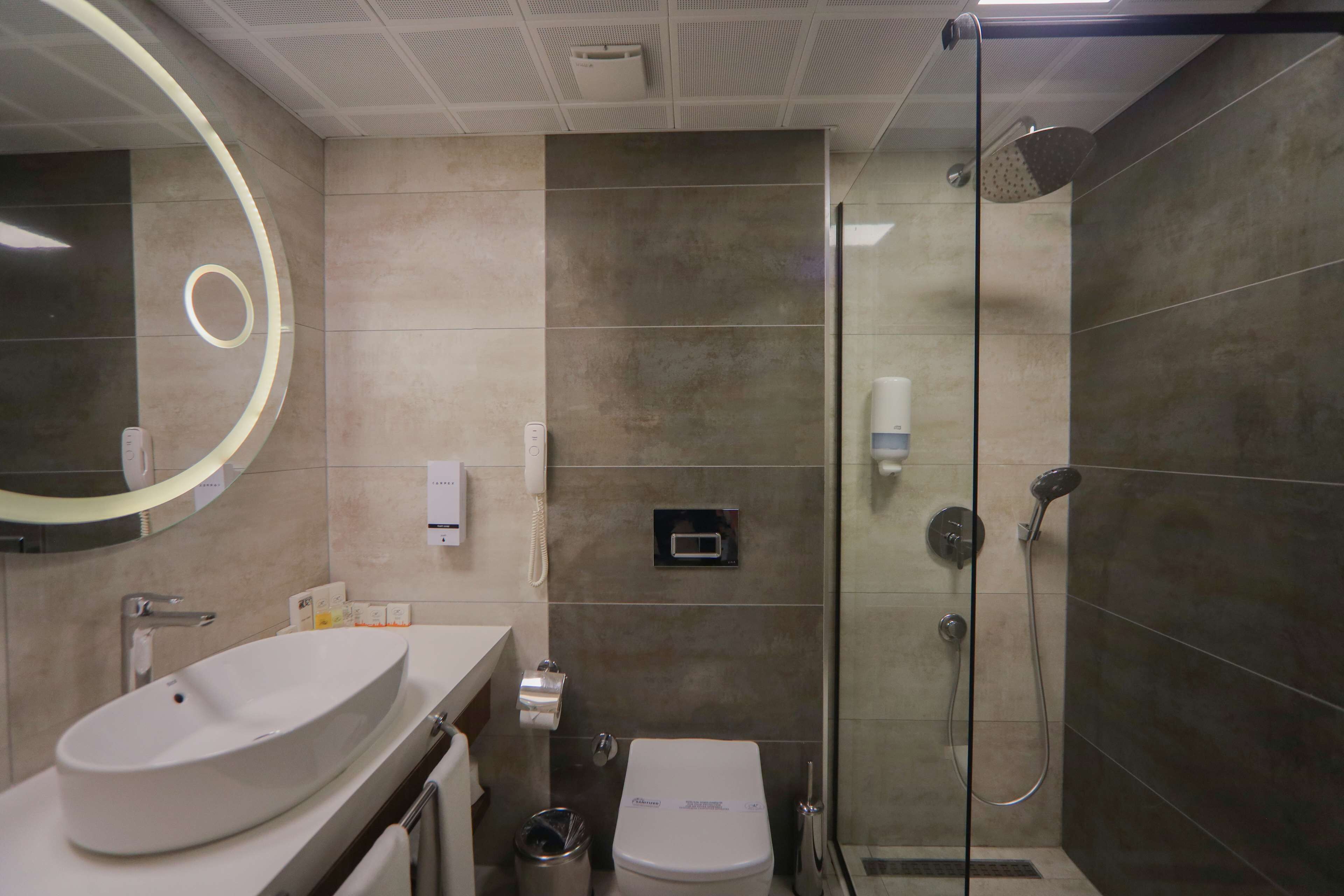 A modern bathroom with a large oval sink, a toilet, and a glass-enclosed shower area.