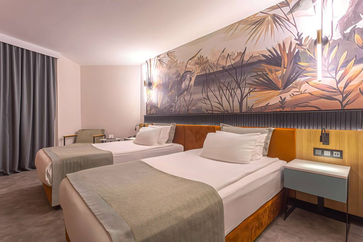 Een hotelkamer met twee bedden, een groot wanddecor, een nachtkastje en een stoel.