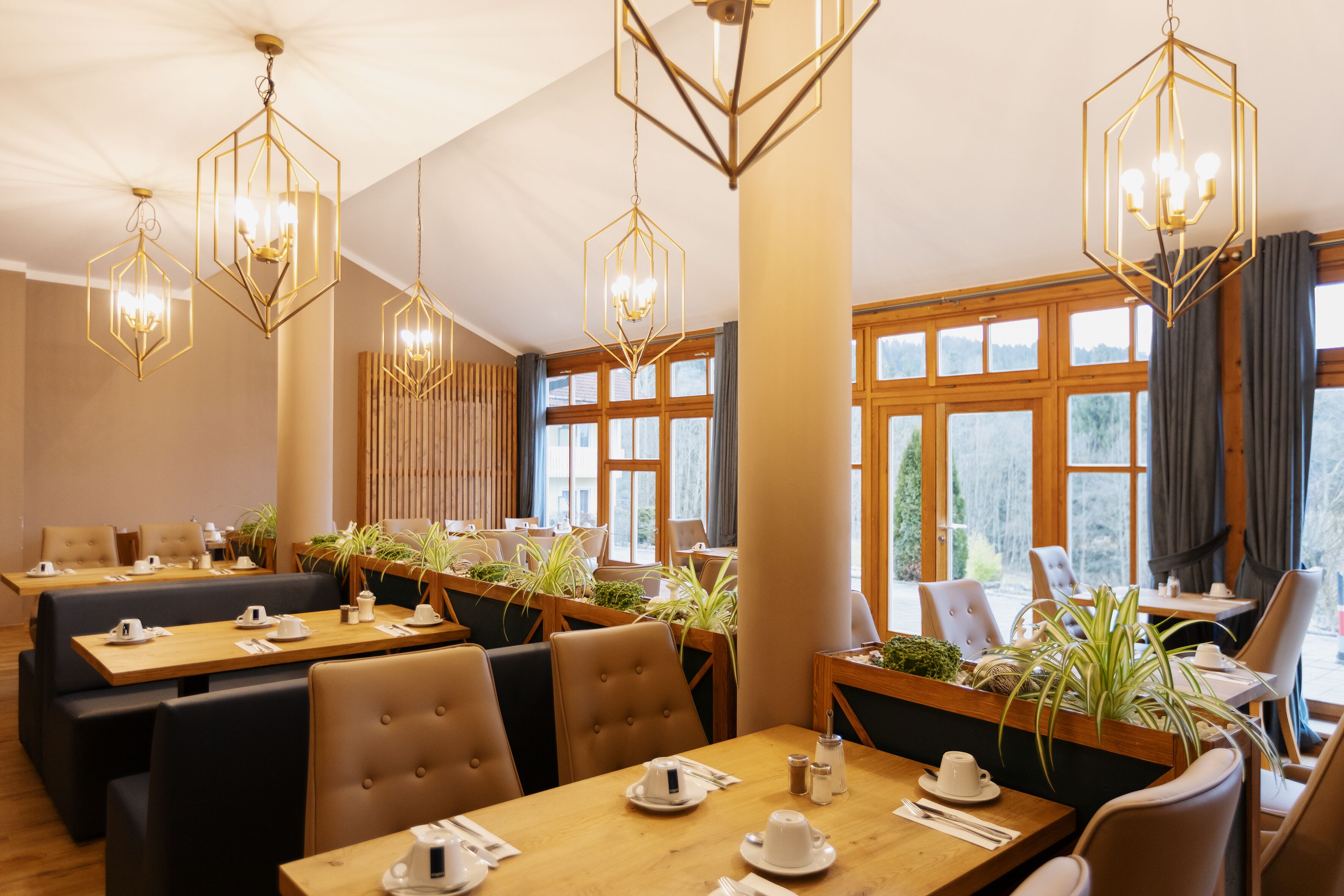 En restaurant med sekskantede lysekroner, træborde og stole.