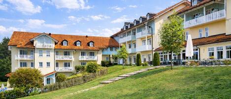A multi-story hotel with balconies, a grassy lawn, and a clear sky.