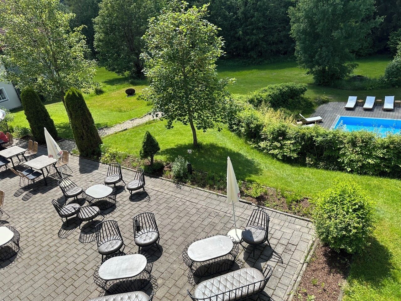 Een terras buiten met zitplaatsen en een zwembad.
